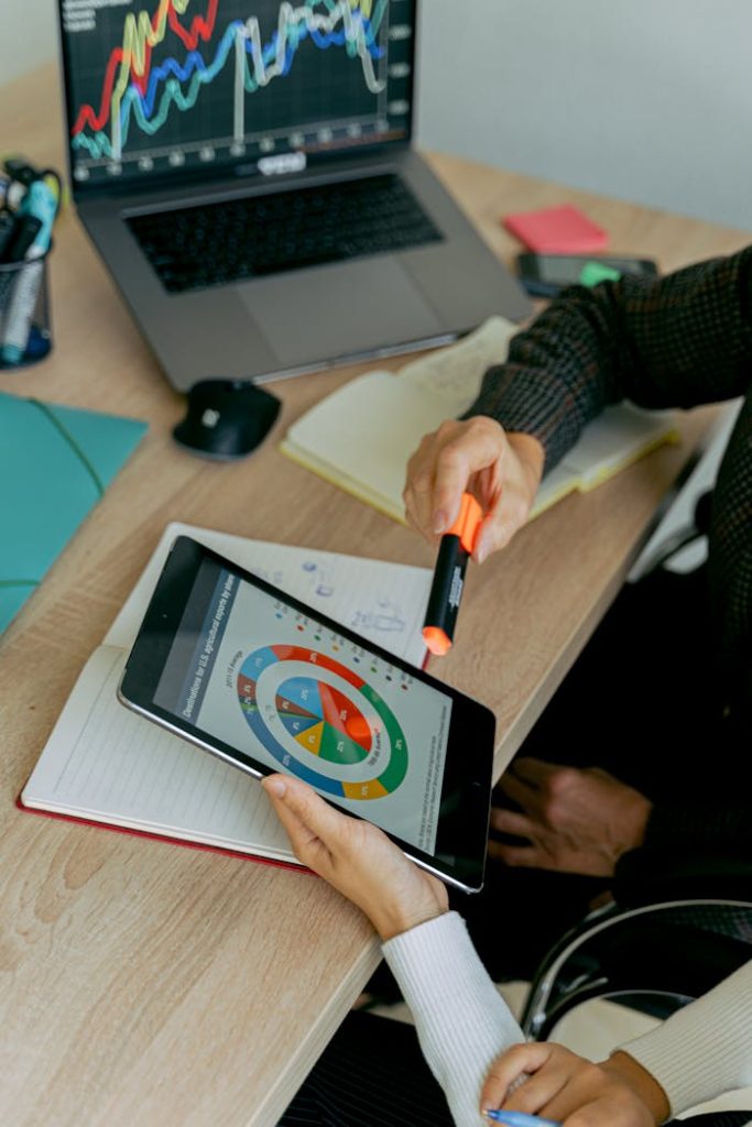 person-holding-black-ipad-on-brown-wooden-table-5862374 Business professionals analyzing data on tablet during a meeting with laptops and charts.